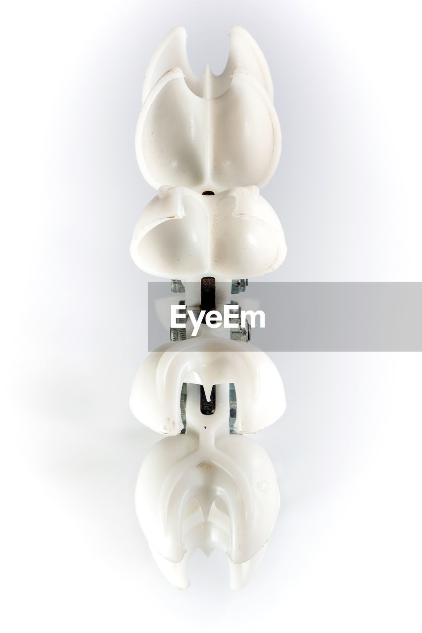 CLOSE-UP OF WHITE LIGHT BULB AGAINST GRAY BACKGROUND