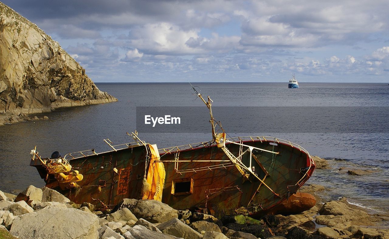 ABANDONED SHIP ON SEA AGAINST SKY