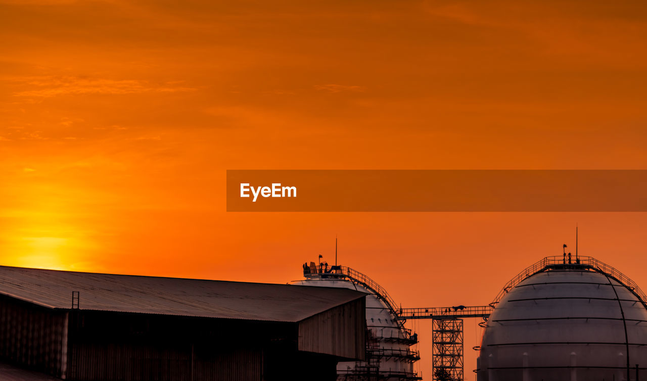 Industrial gas storage tank. lng or liquefied natural gas storage tank. red and orange sunset sky. 