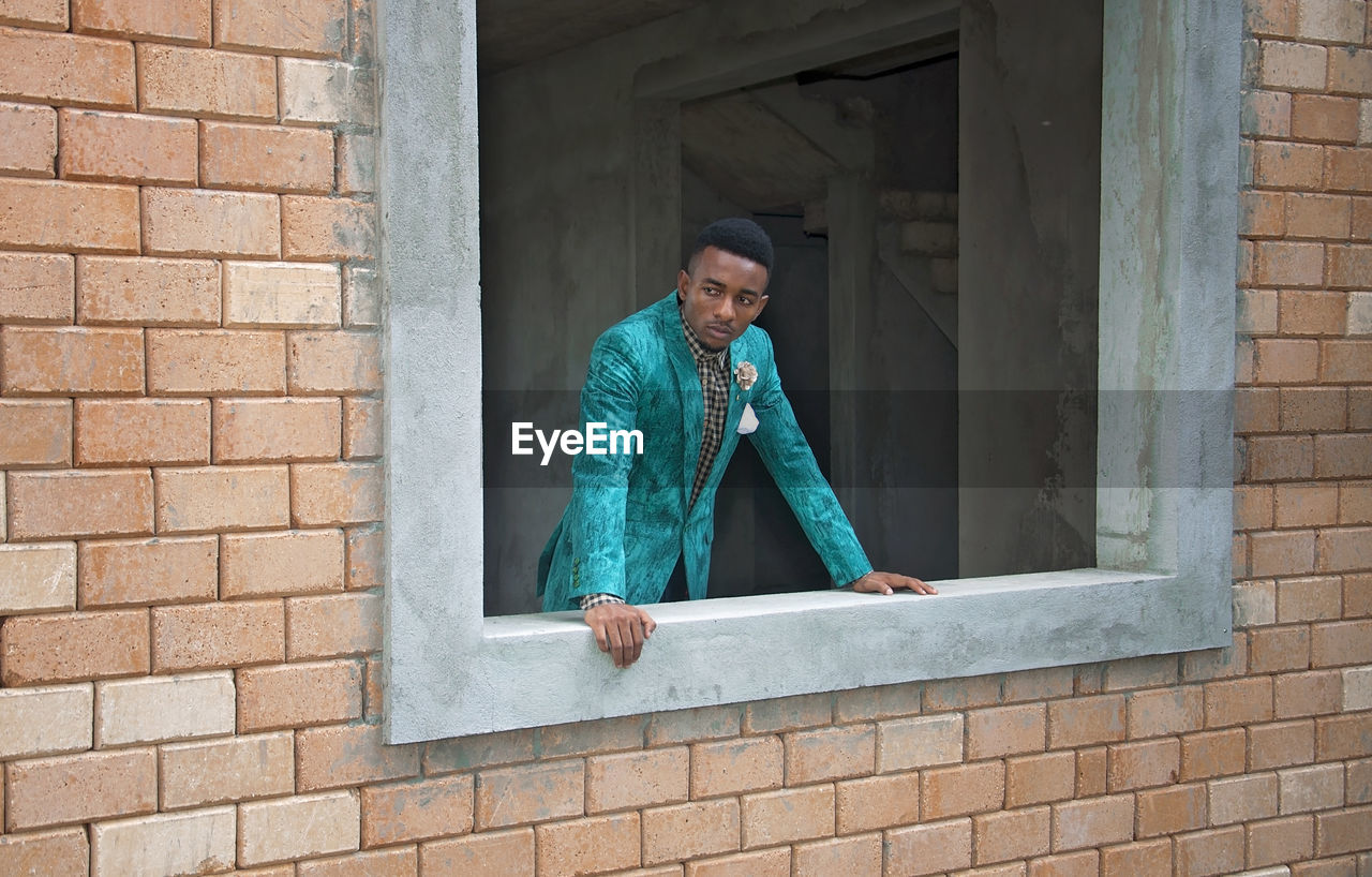 Man looking away while peeking through window