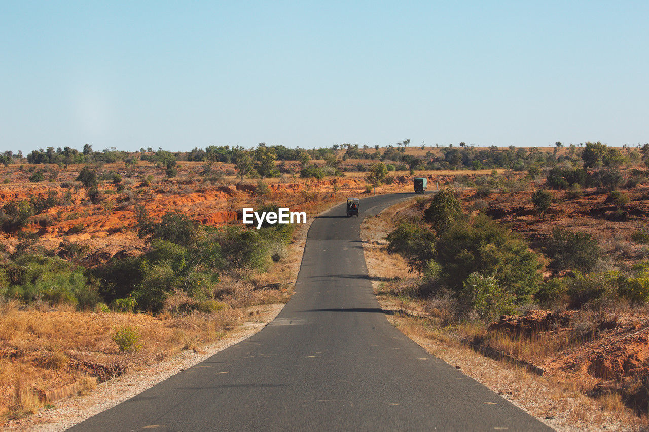 road, landscape, sky, environment, nature, the way forward, transportation, scenics - nature, plant, clear sky, natural environment, diminishing perspective, hill, no people, infrastructure, land, beauty in nature, tree, vanishing point, non-urban scene, soil, travel, rural area, tranquility, highway, outdoors, day, tranquil scene, travel destinations, semi-arid, copy space, sunny, remote, horizon, sunlight, country road, road trip, tourism, footpath, blue, desert, empty road