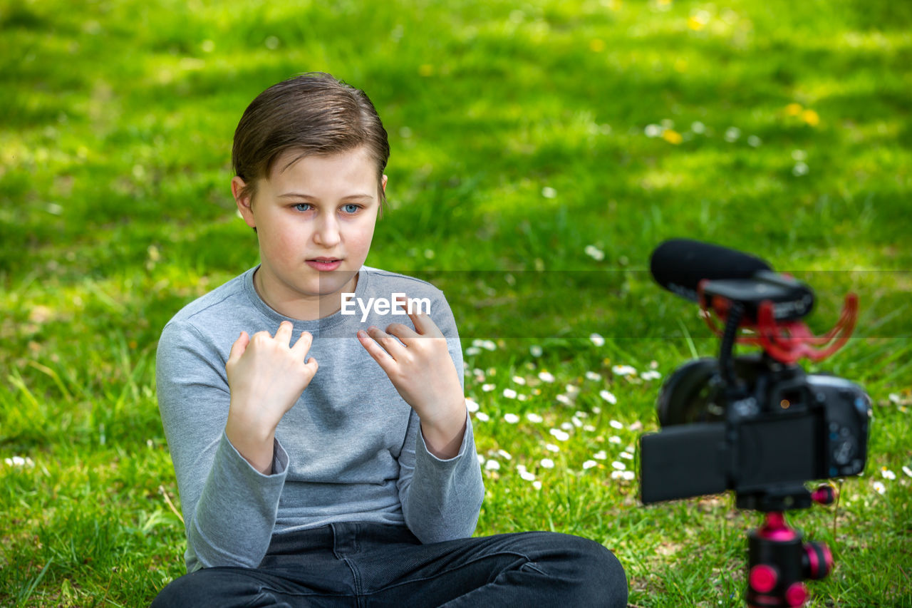 PORTRAIT OF A BOY SITTING ON FIELD