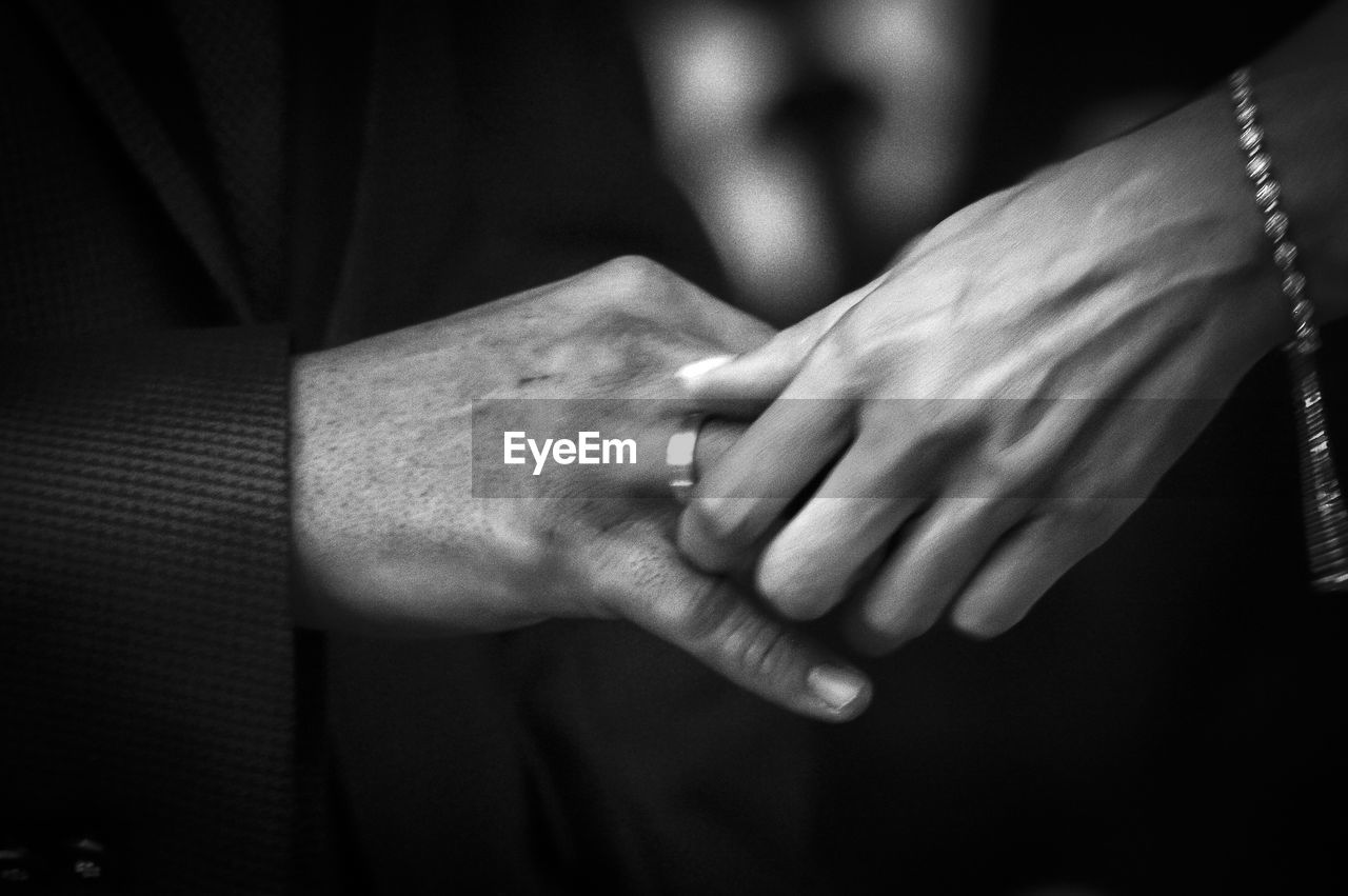 Cropped hand of bride putting ring in groom finger