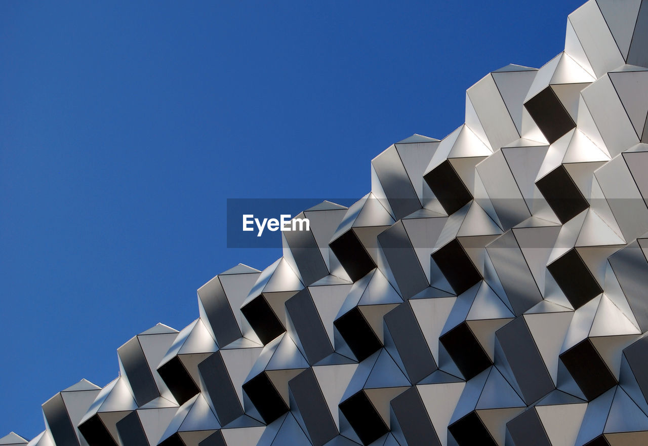 Low angle view of modern built structure against clear blue sky