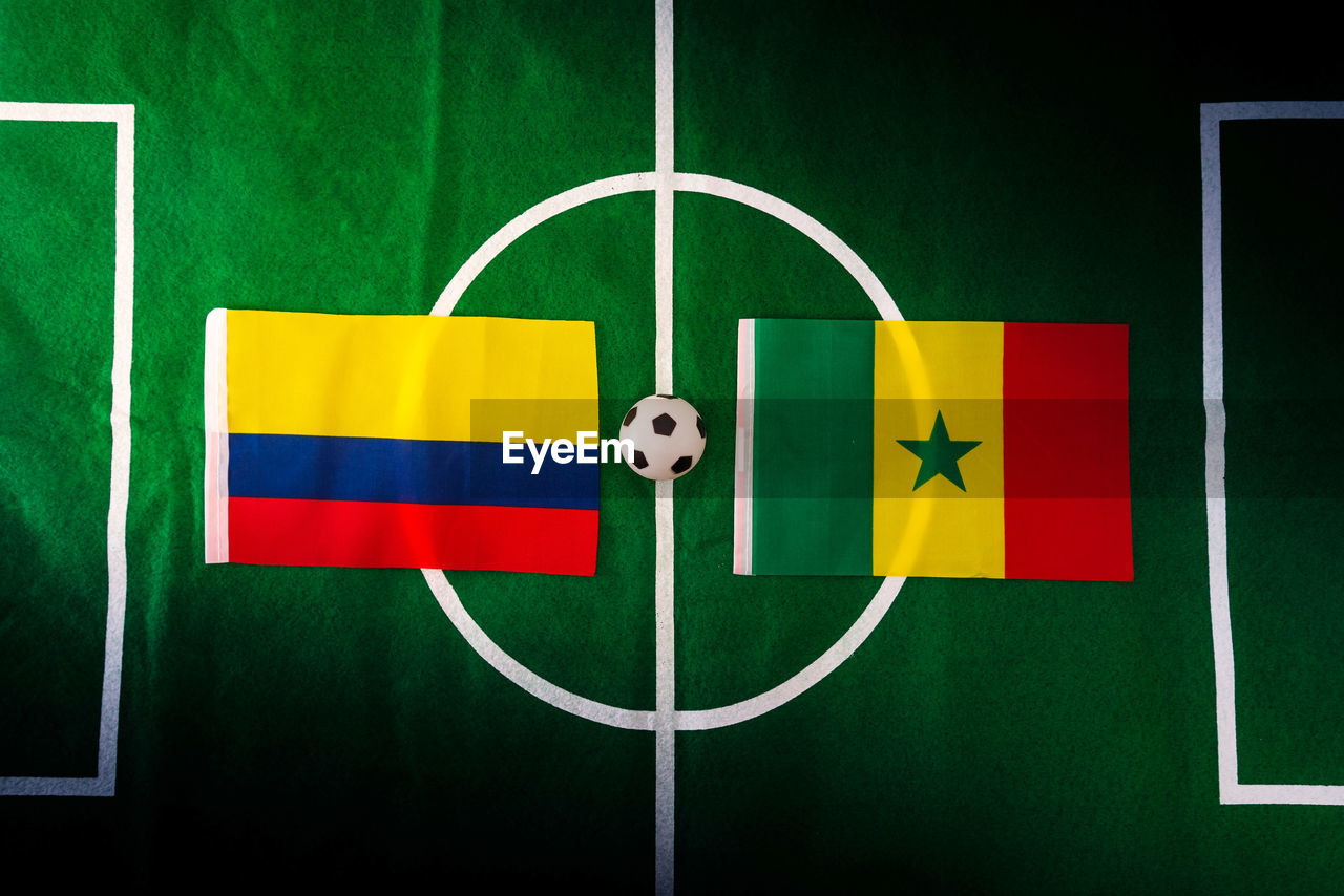 Directly above shot of figurine soccer field with flags of colombia and senegal 