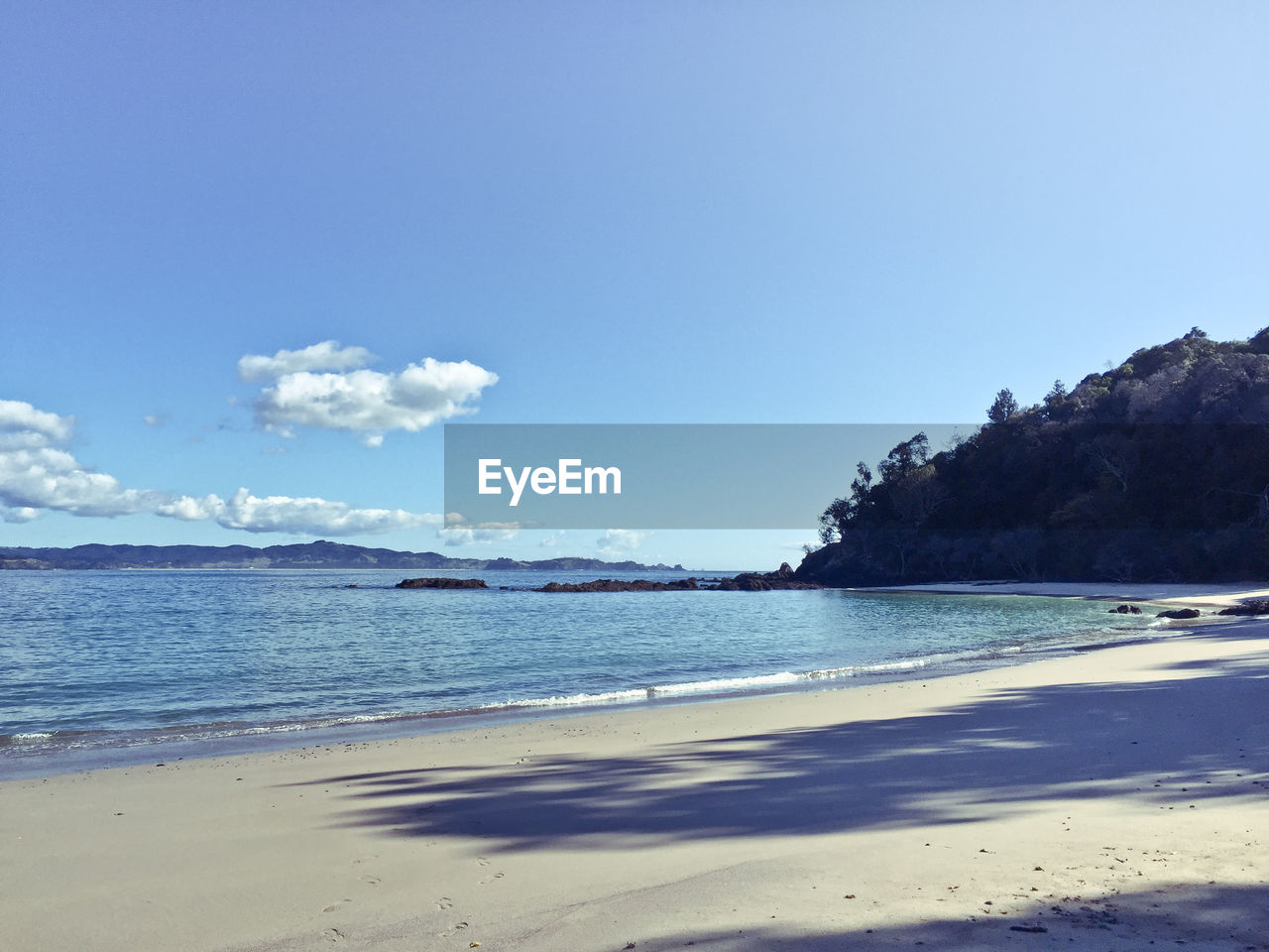 View of calm beach against blue sky