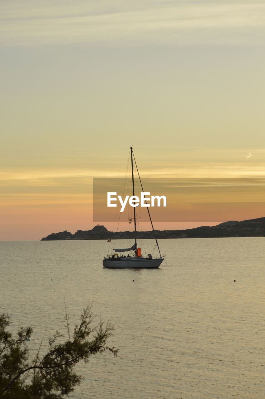 Sailboat sailing on sea against sky during sunset