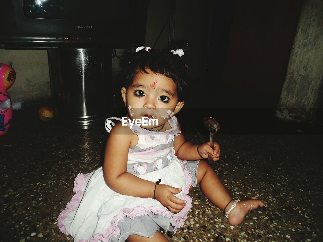 Portrait of baby girl with messy face sitting on floor at home