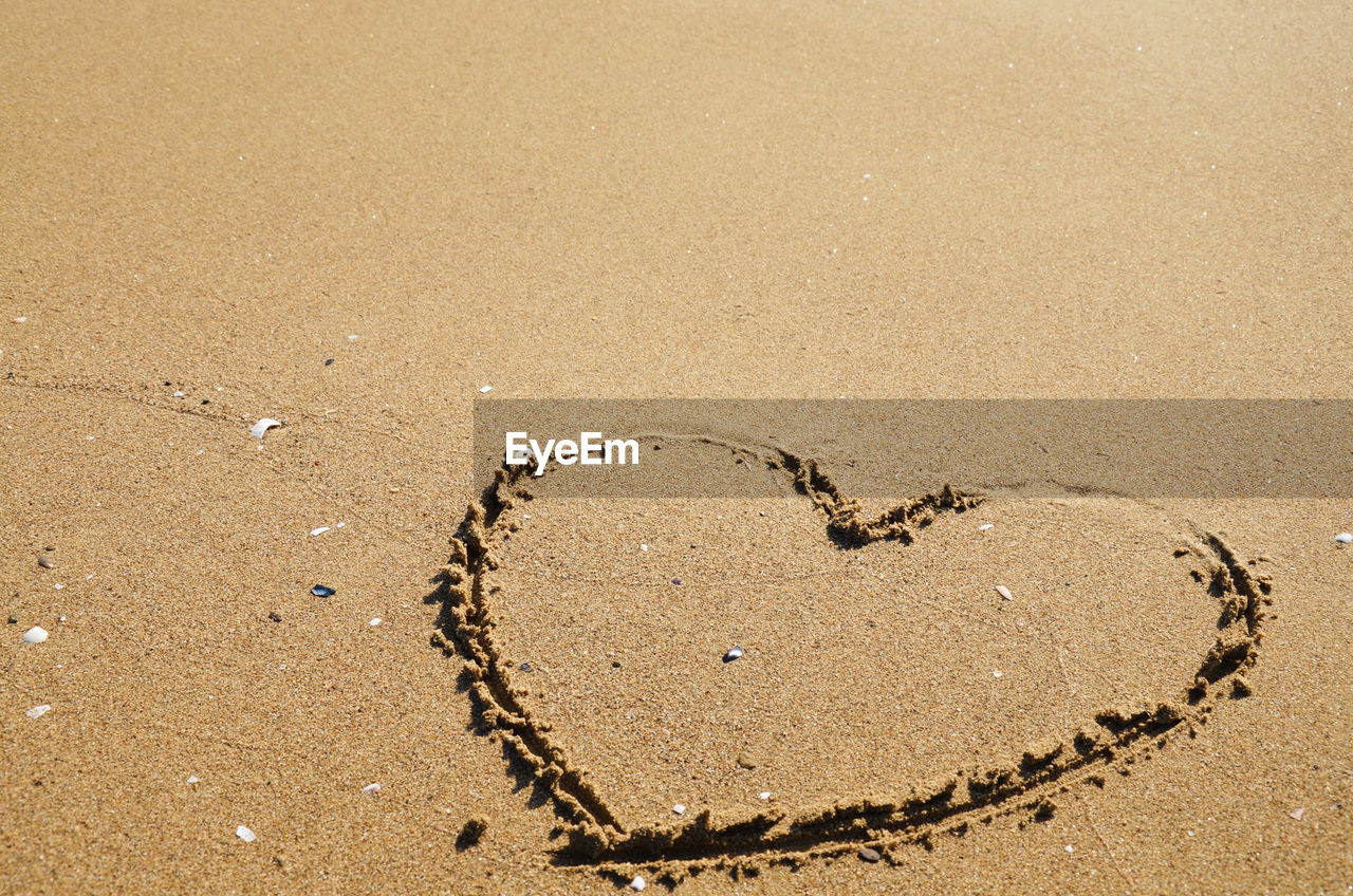 Close-up of heart shape on sand at beach