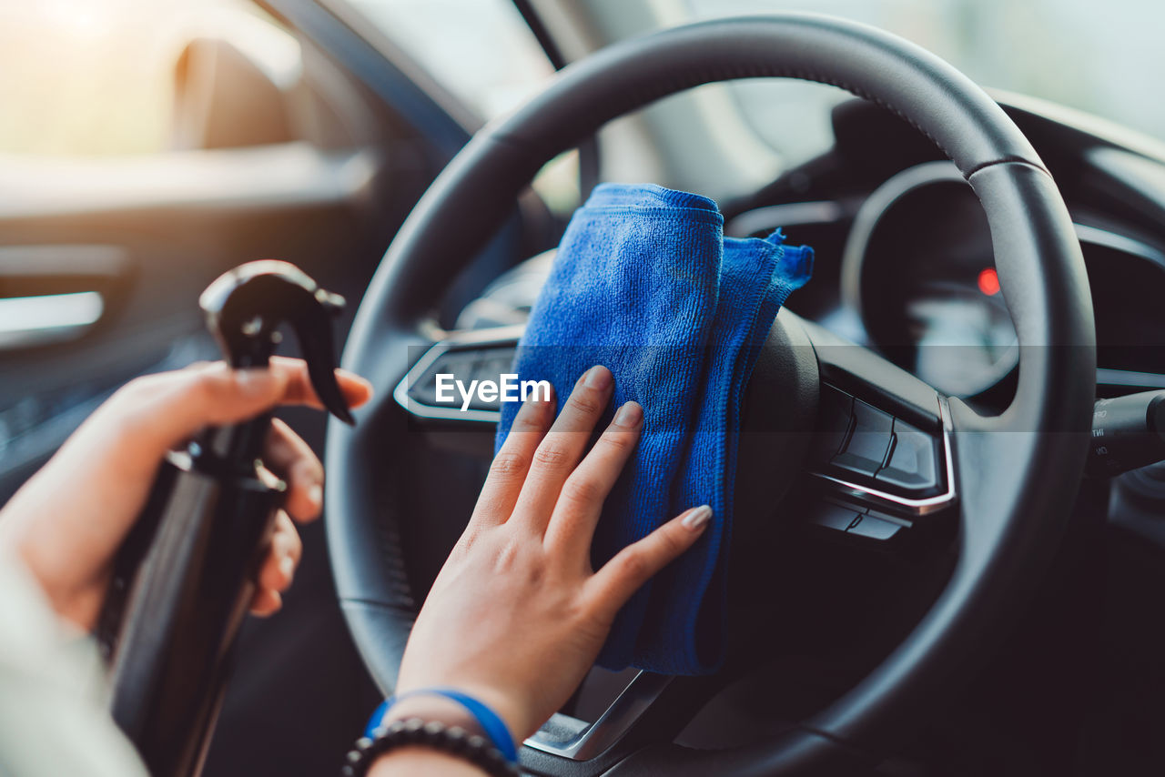 Cropped hands of woman cleaning car steering wheel