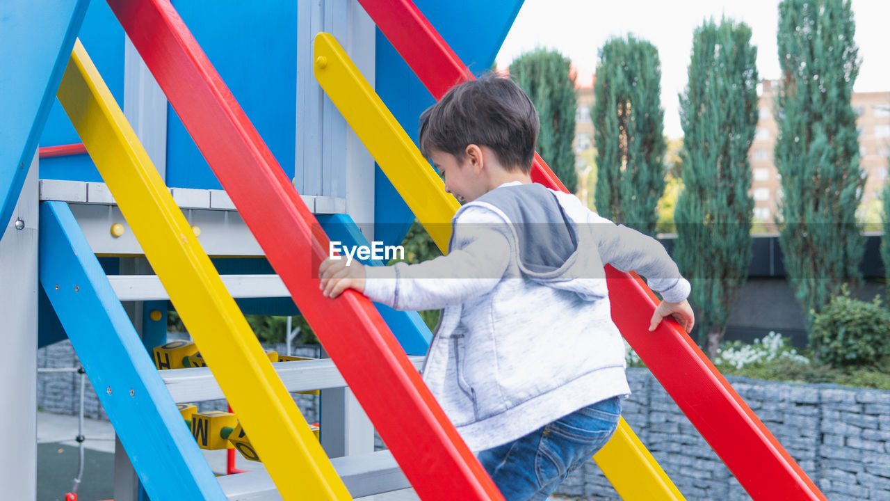 SIDE VIEW OF MAN PLAYING ON PLAYGROUND