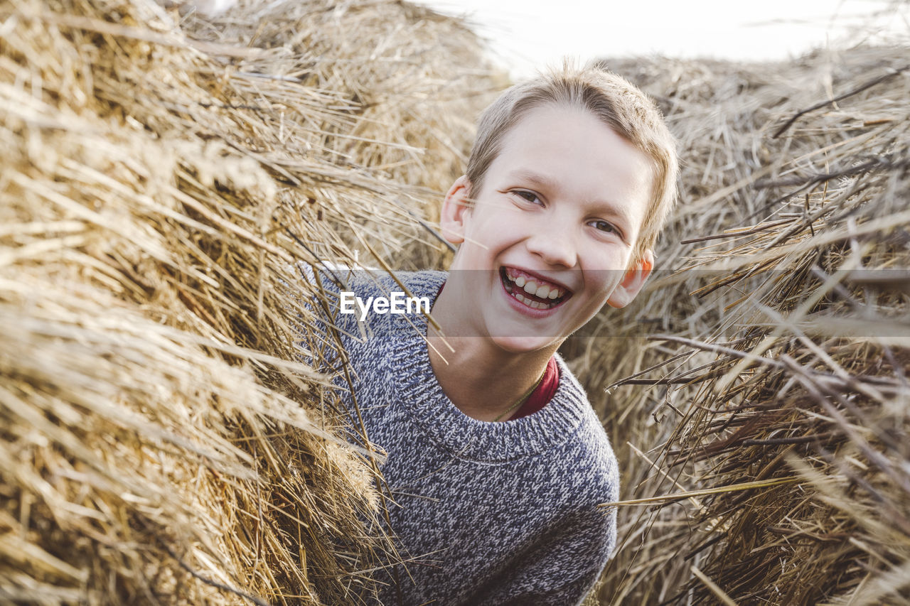 Cheerful boy peeking from haystack