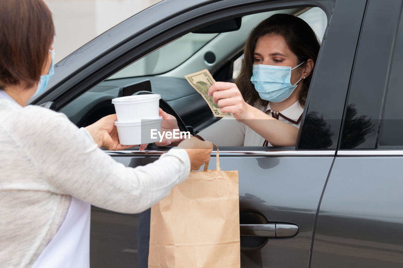 Midsection of woman holding drink while sitting in car