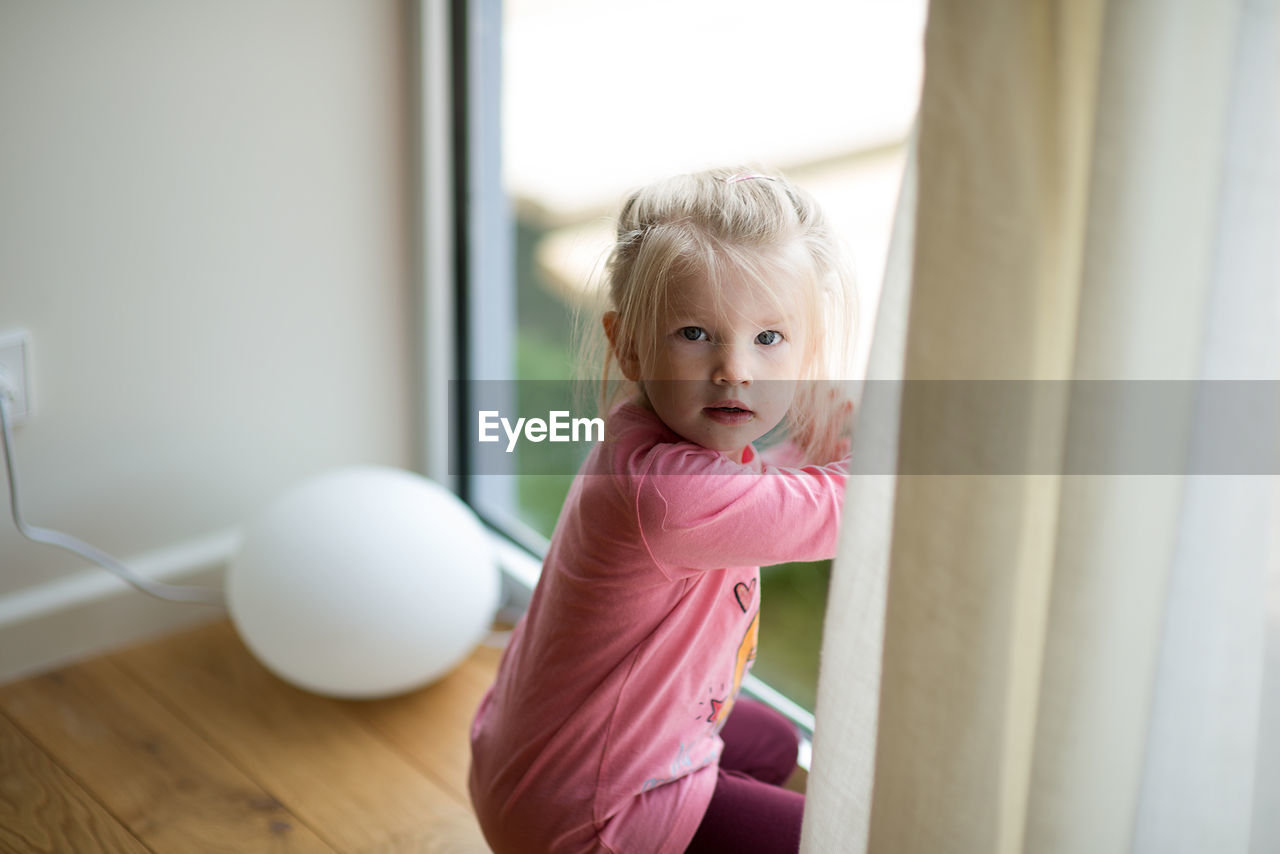 Cute girl sitting by door at home