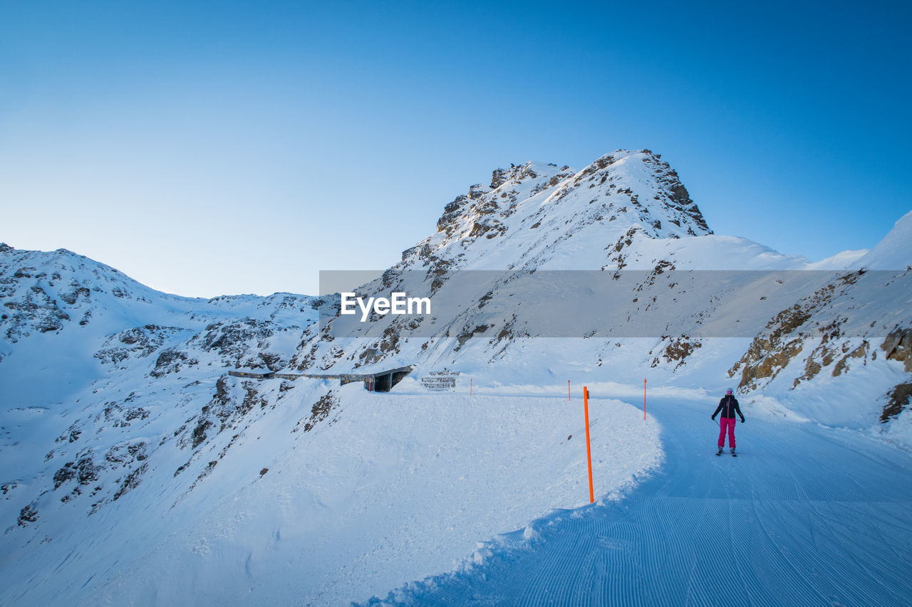 Person skiing on snowcapped mountain against clear sky