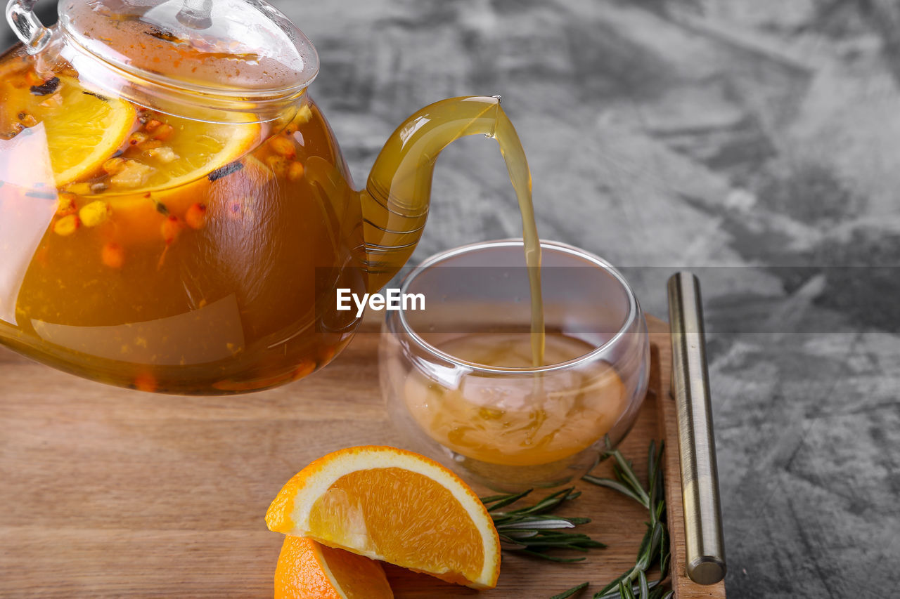 Cropped image of teapot pouring drink in drinking glass