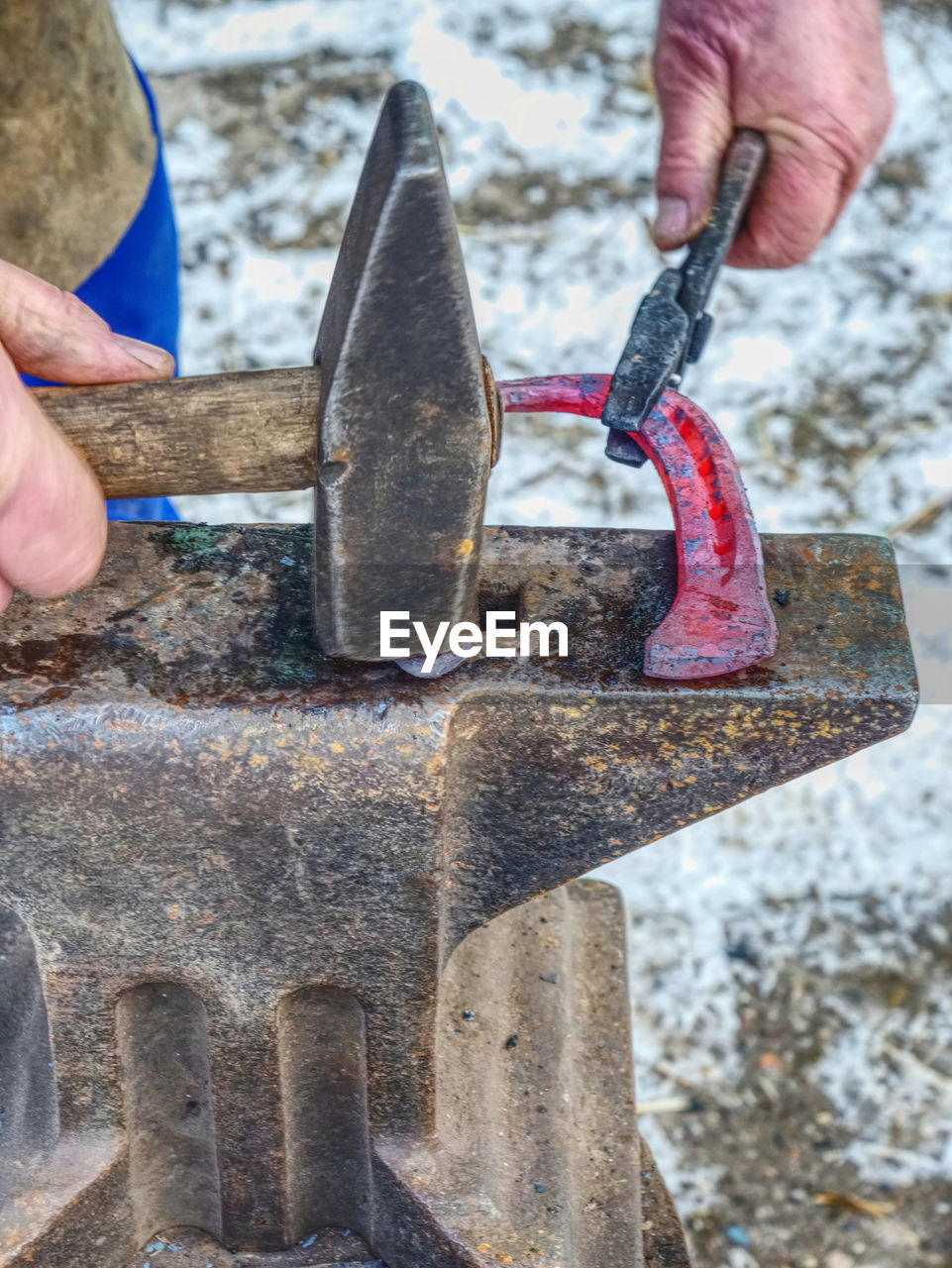 Blacksmith forges hot horseshoe. farrier is making horseshoe hitting with a hammer on the anvil