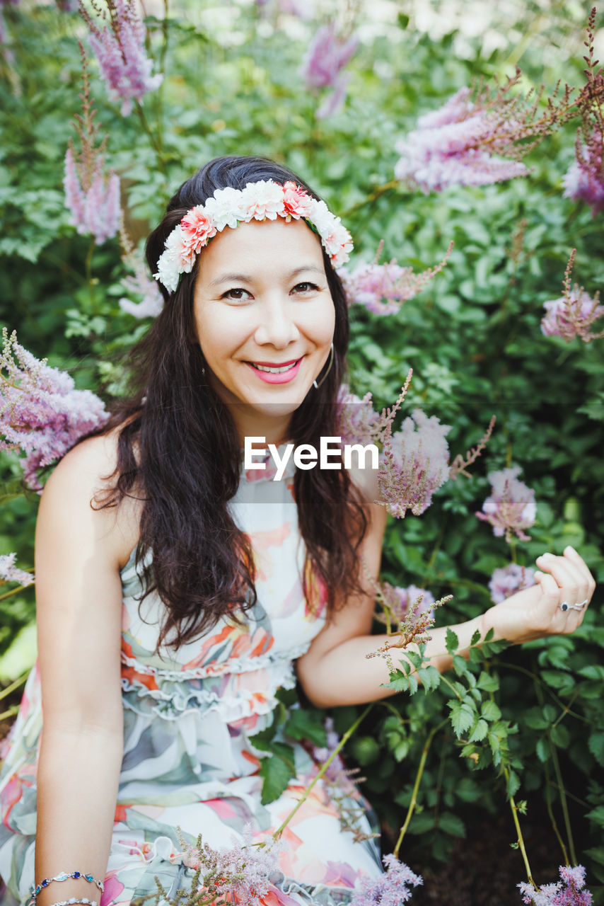 Happy mixed-race japanese woman with flower hair band in garden
