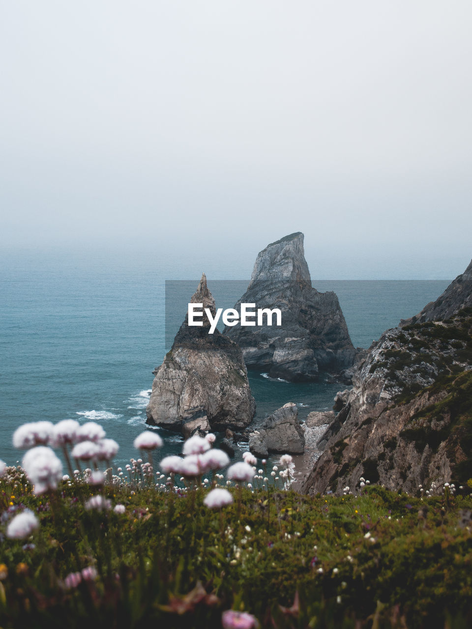 Scenic view of rocks by sea against sky