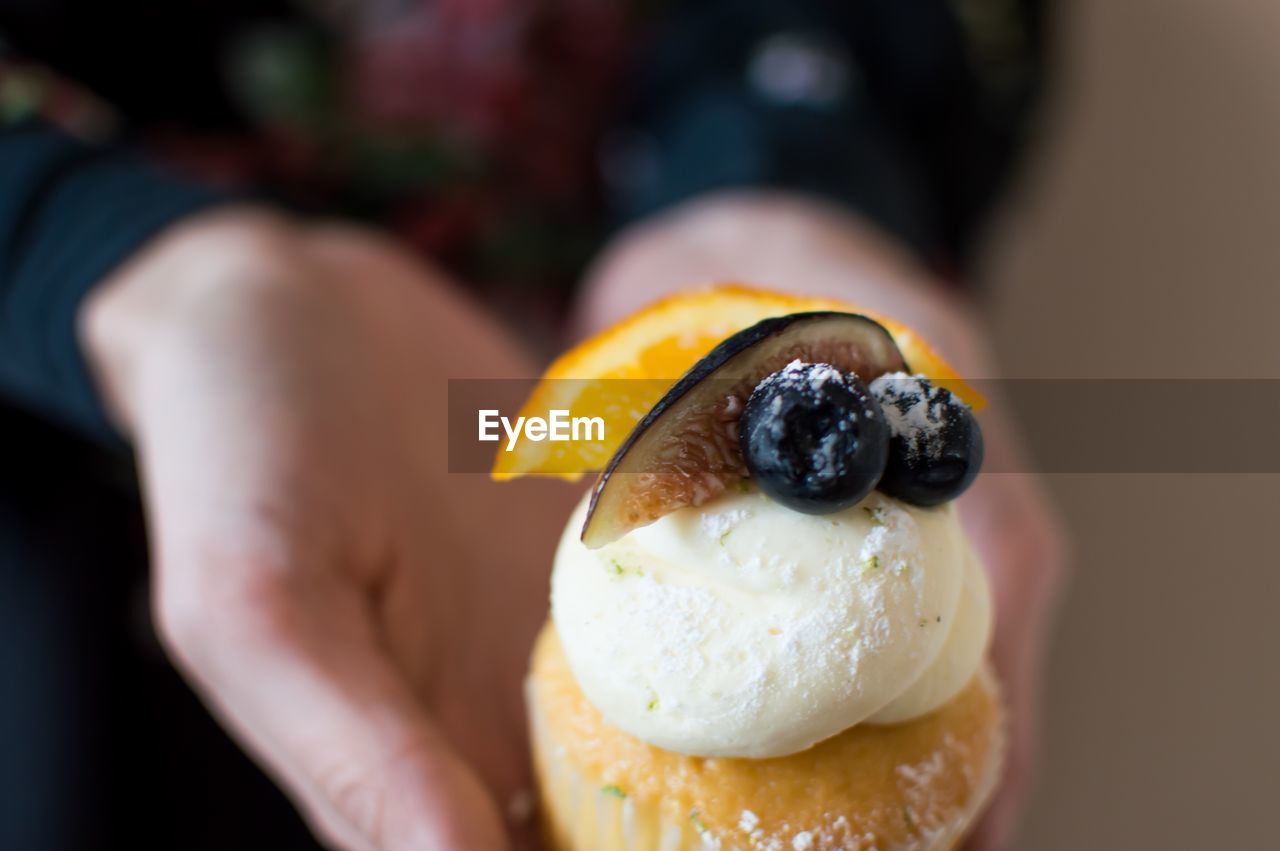 Cropped image of woman holding cupcake with ice cream