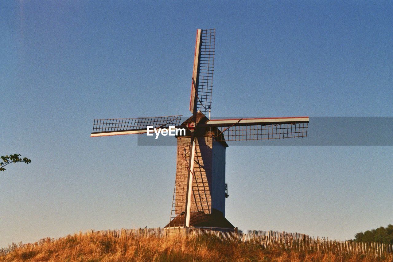 TRADITIONAL WINDMILL ON FIELD AGAINST CLEAR SKY