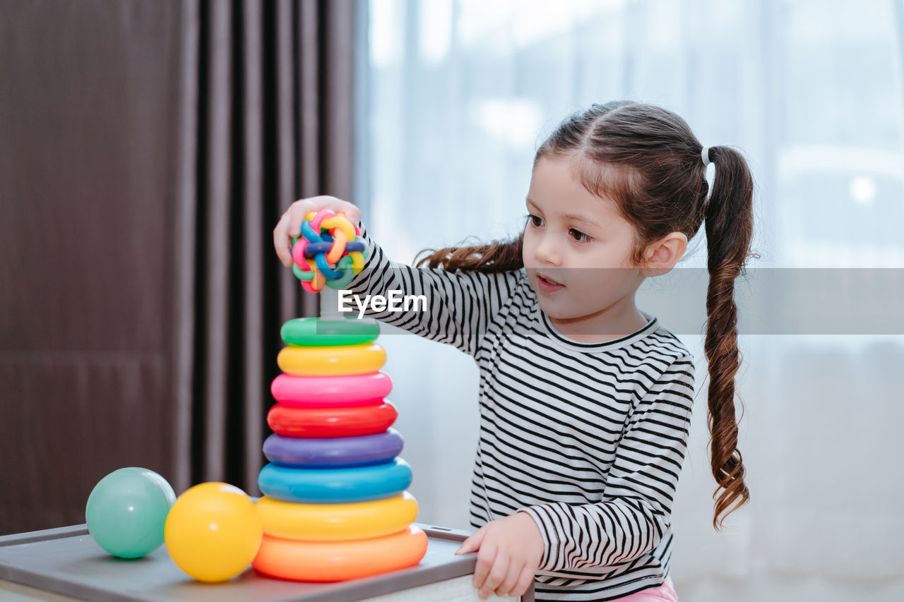 Girl playing with multi colored toys at home