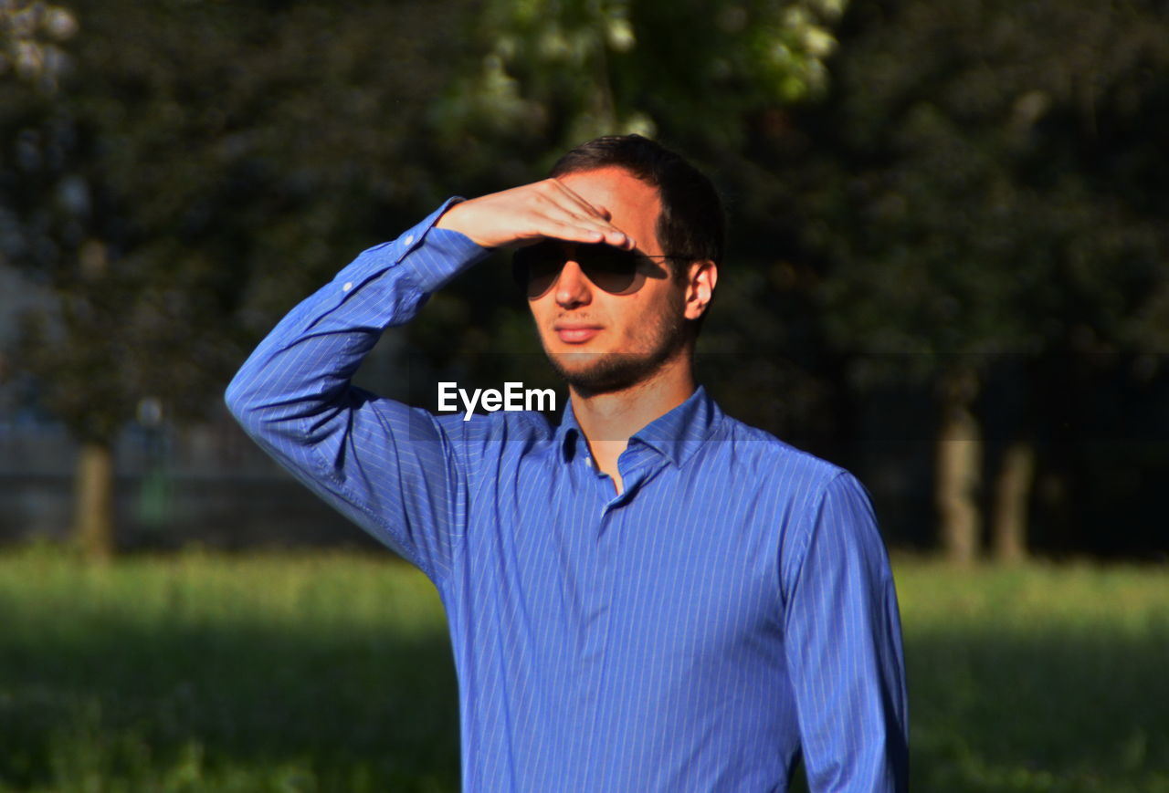 Young man shielding eyes on sunny day