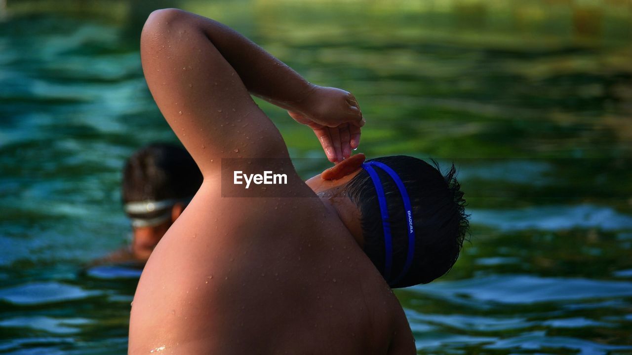 Rear view of shirtless boy swimming in lake