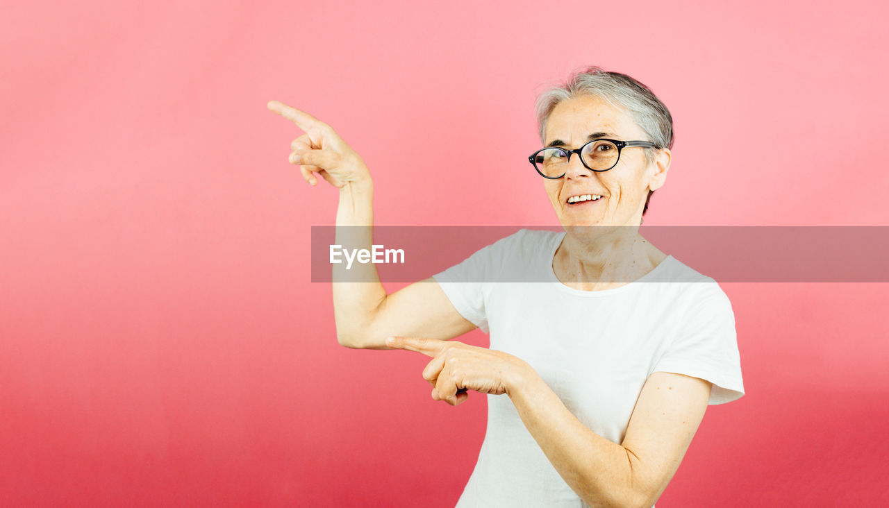 portrait of young woman with arms raised against yellow background