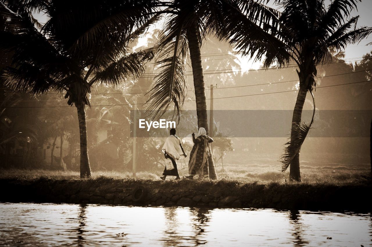 People walking on field by lake