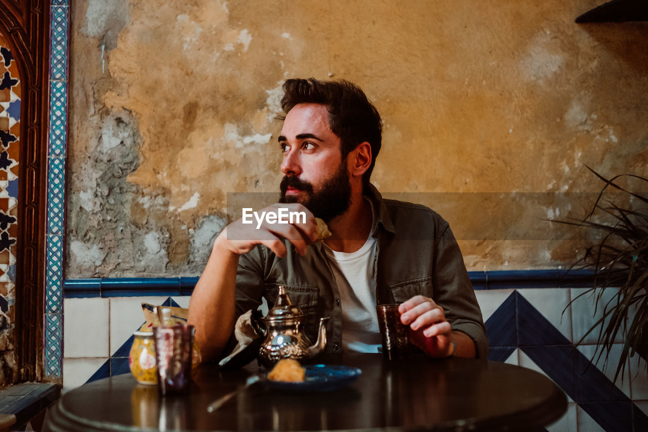 Man eating food while sitting on table in restaurant