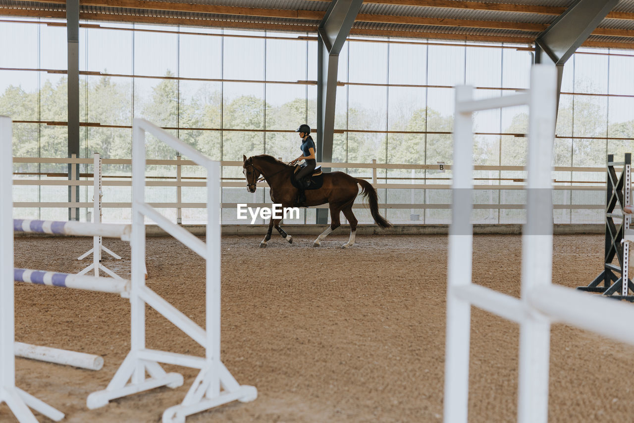 View of female horse rider using indoor riding paddock