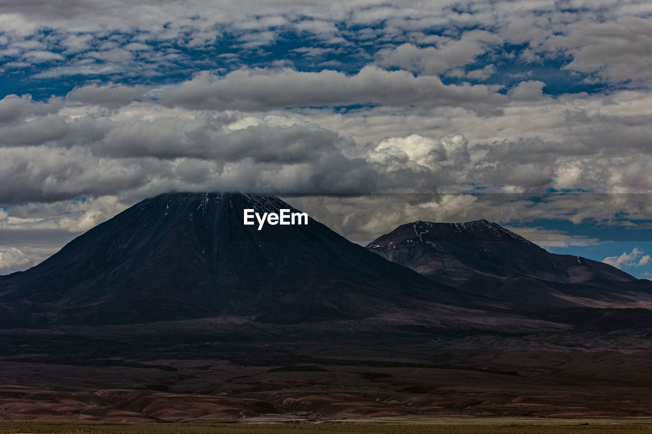 Scenic view of mountain range against cloudy sky