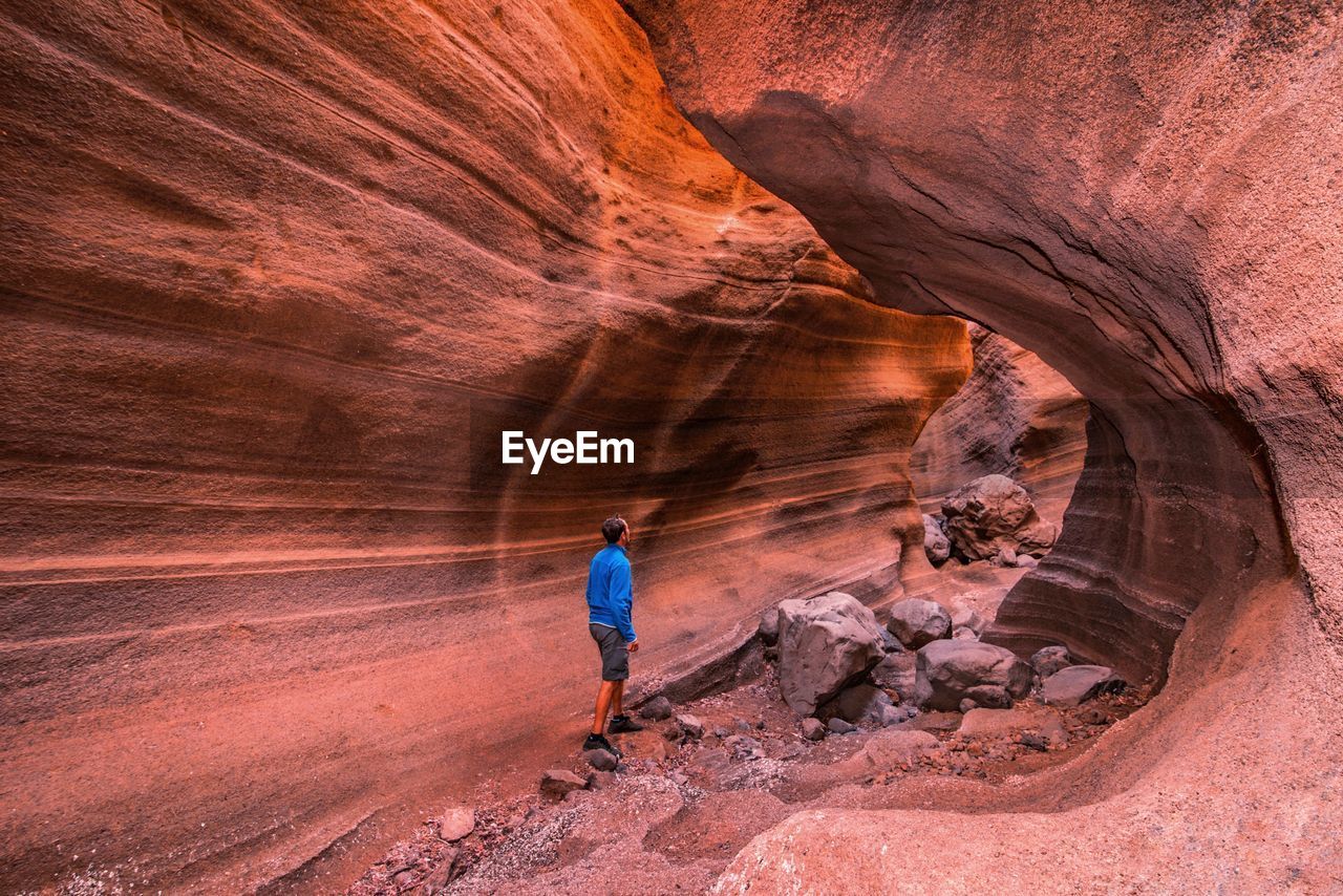 Rear view of man standing amidst rock formation