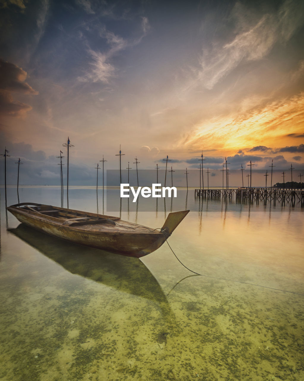 Sailboats moored on sea against sky during sunset