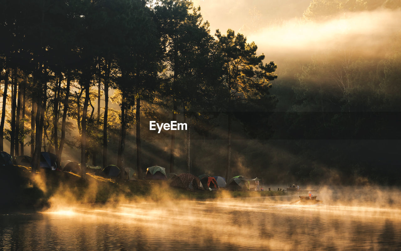 Idyllic lake by tents during foggy weather