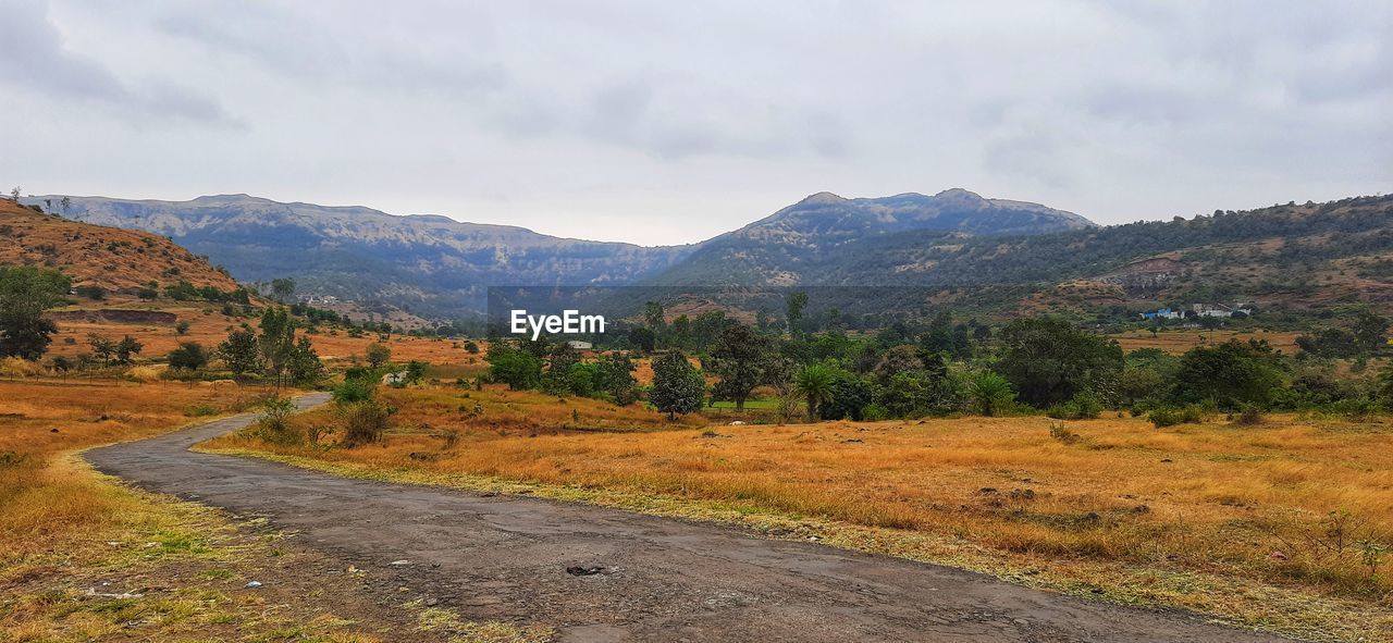 SCENIC VIEW OF ROAD BY MOUNTAINS AGAINST SKY