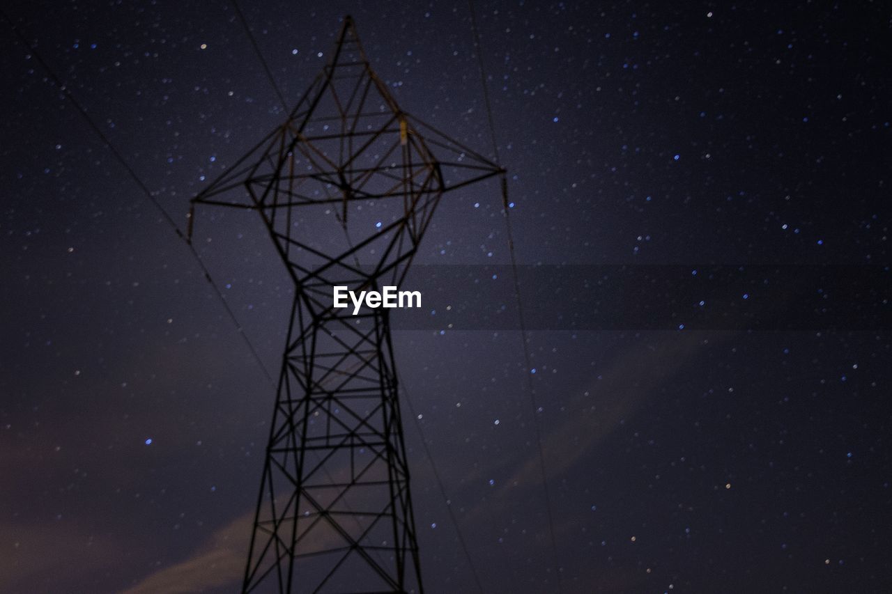 Low angle view of electricity pylon against starry sky