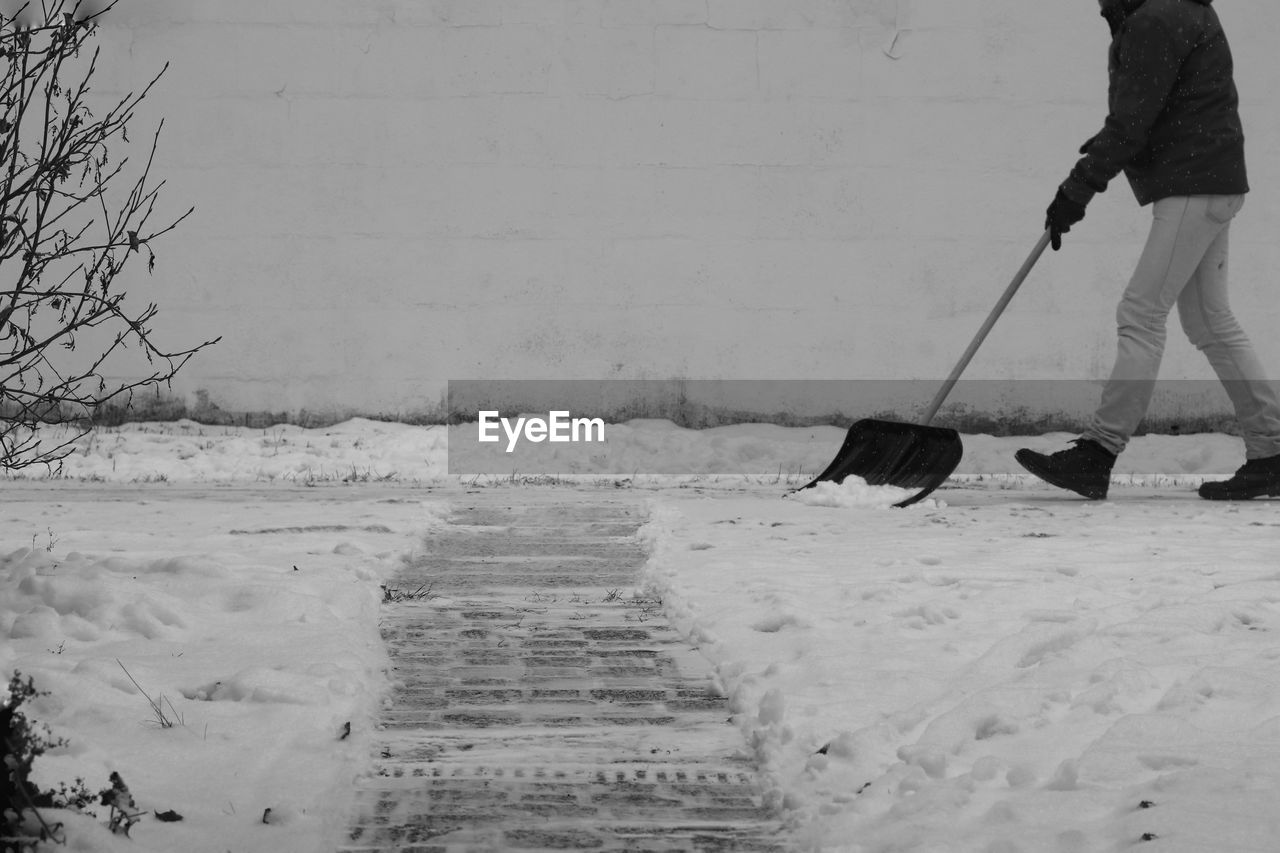 Low section of person with snow shovel on snow