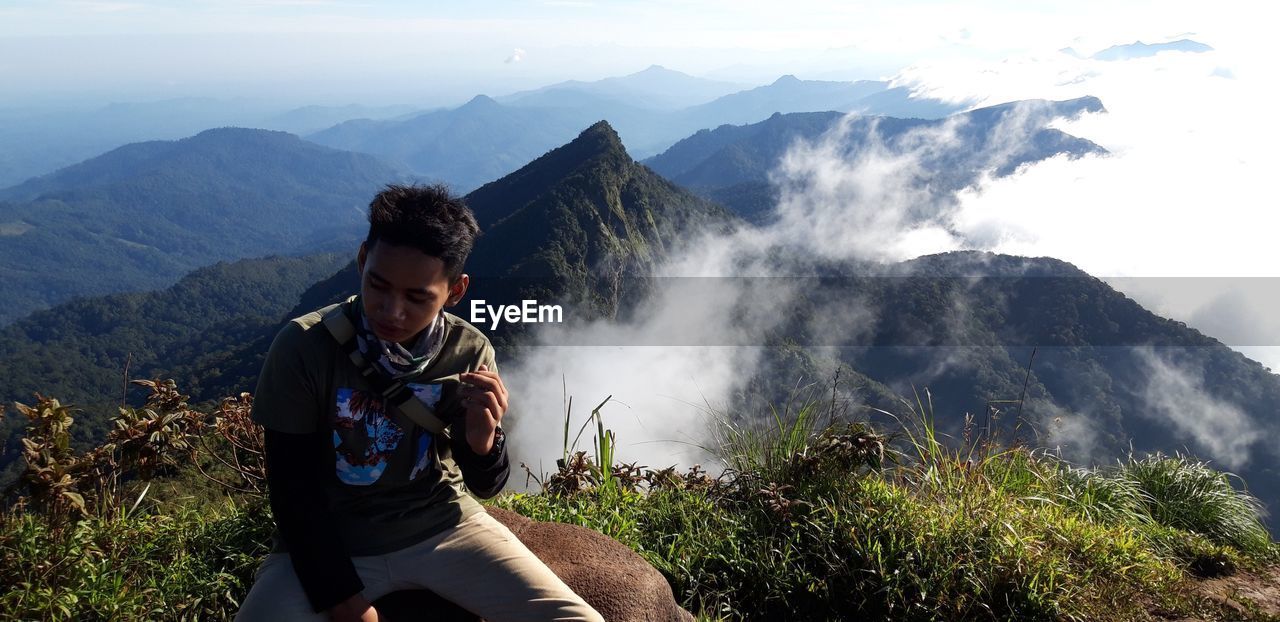 YOUNG MAN AGAINST MOUNTAINS AGAINST SKY