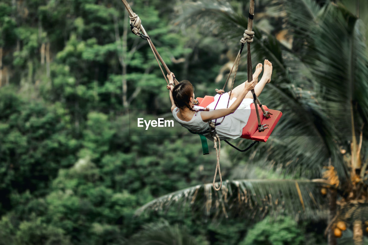 MIDSECTION OF WOMAN HANGING ON ROPE