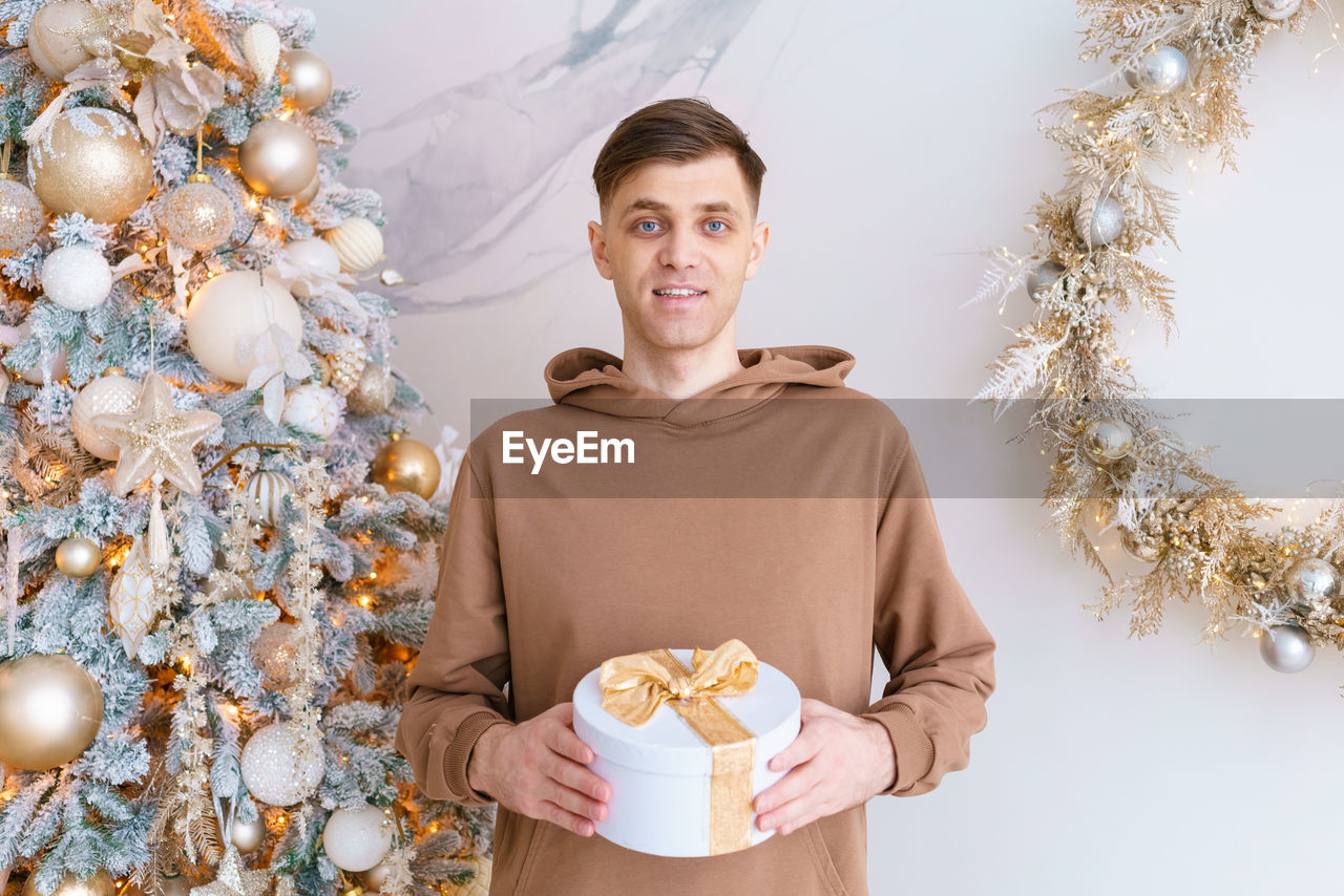 Happy young man opens christmas present. accelerated hipster guy sitting near