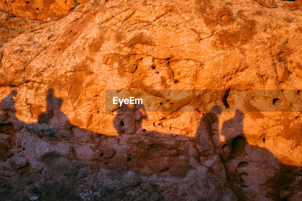 Rock formation with shadows of people on it during the sunset