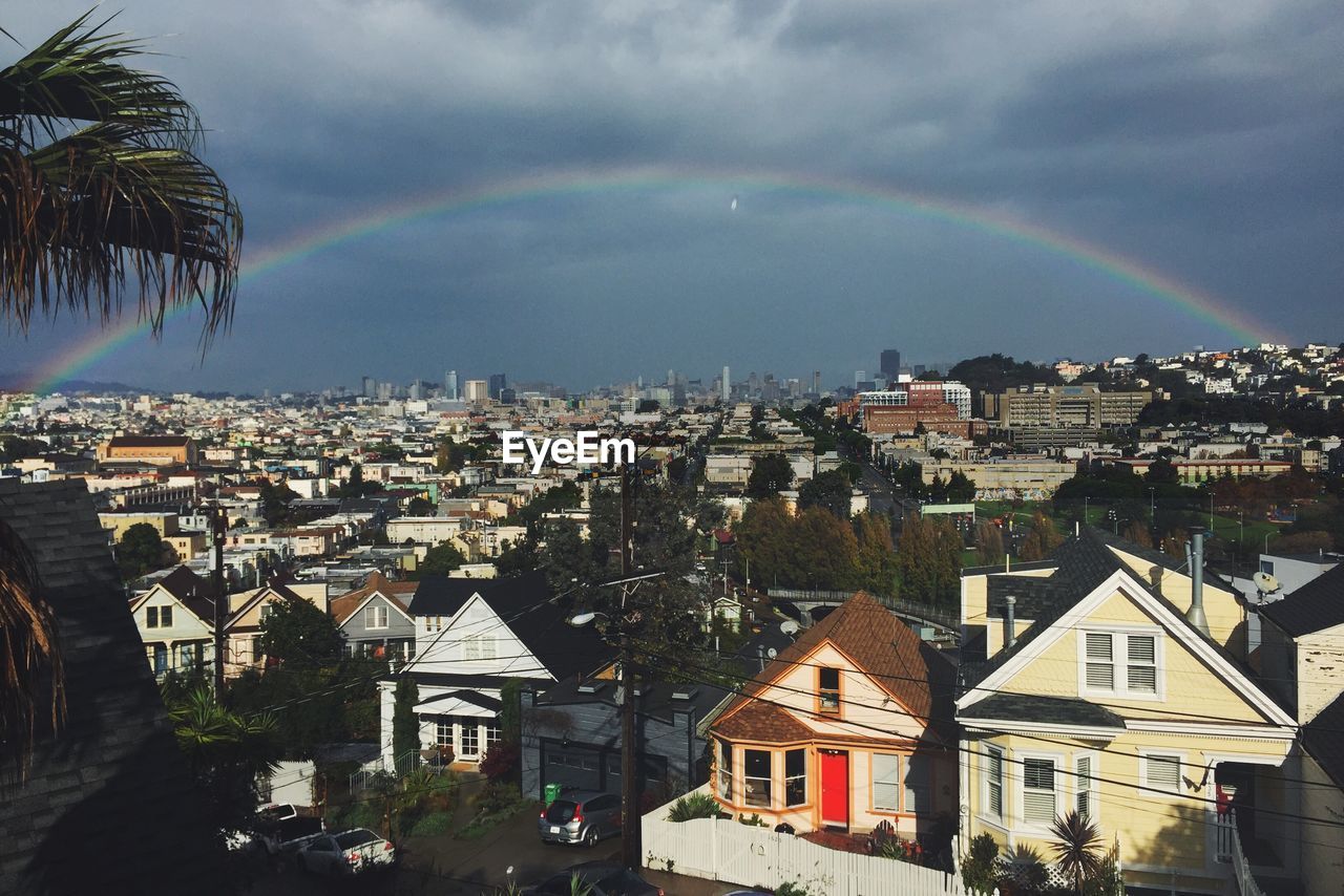 Rainbow over residential district against cloudy sky