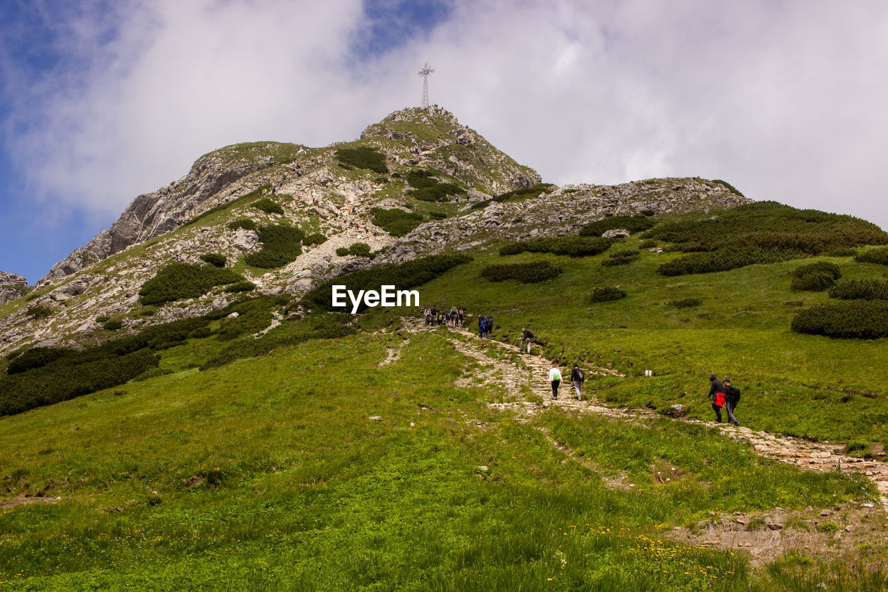 PEOPLE BY MOUNTAIN AGAINST SKY