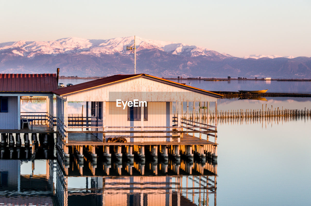 Built structure by lake against clear sky during sunset