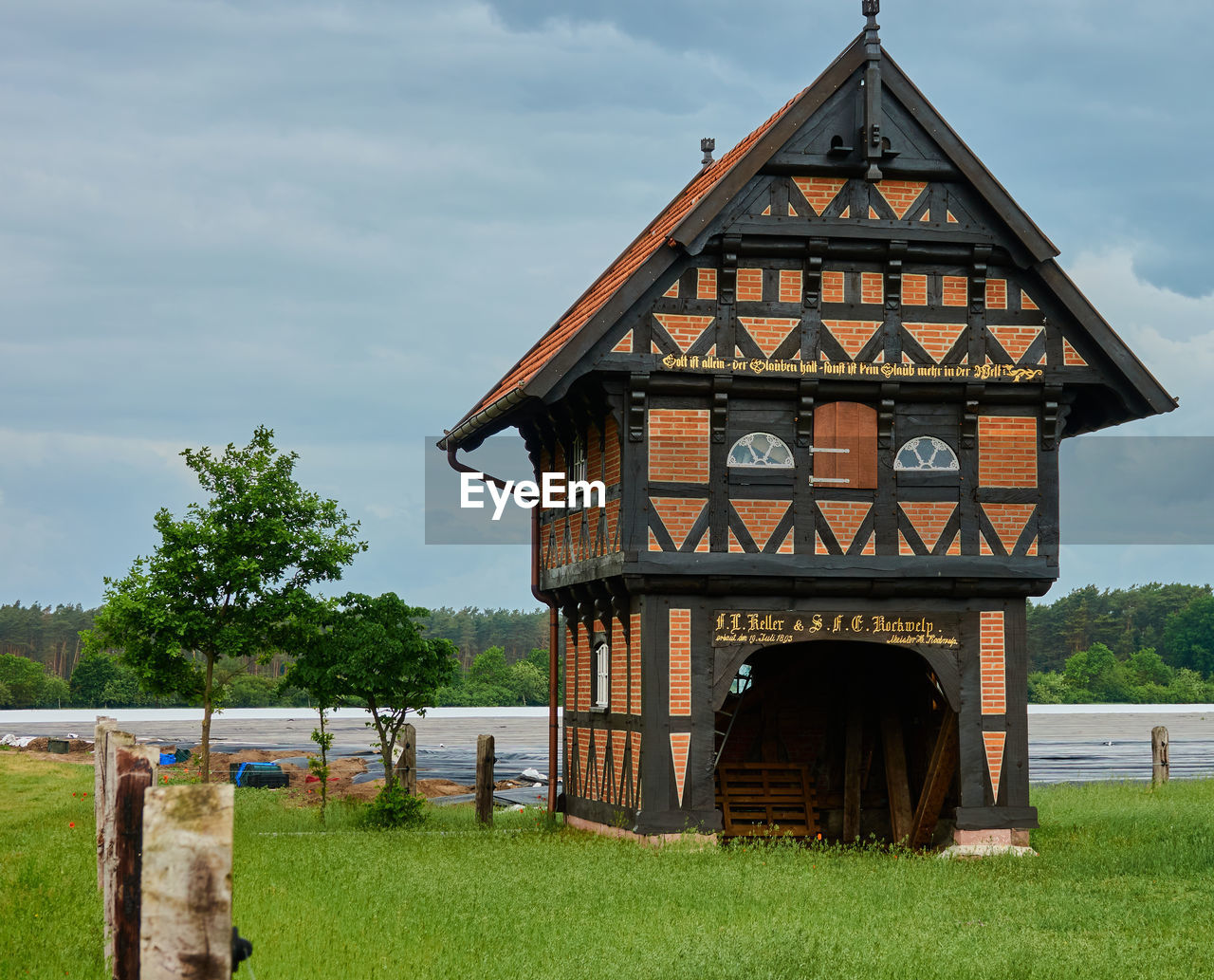 BUILT STRUCTURE ON FIELD BY HOUSE AGAINST SKY