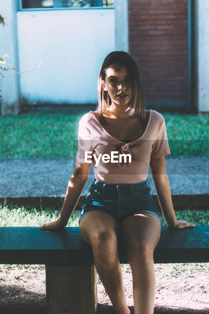 Portrait of teenage girl sitting on bench at park