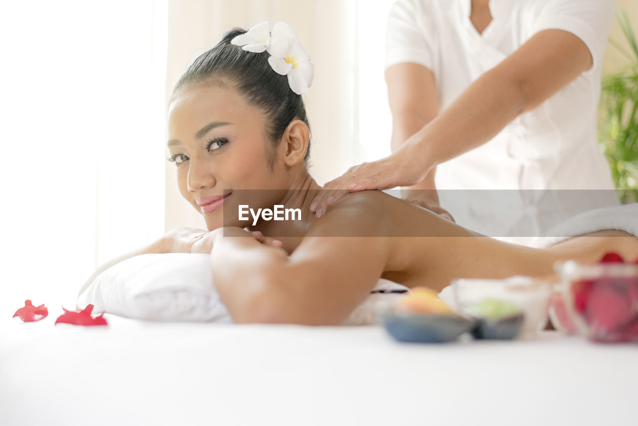 Portrait of shirtless woman receiving massage from therapist