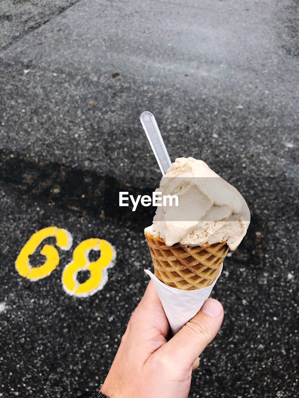 Close-up of hand holding ice cream cone on road